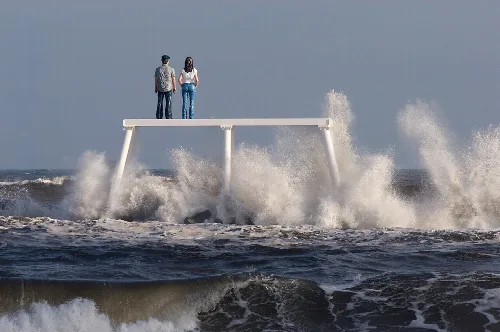 Dos personas en una plataforma blanca sobre las olas del mar.