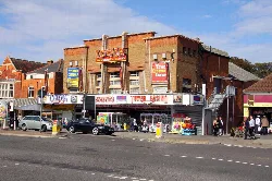 Brick building with Tower Cinema sign, shops, and pedestrians.