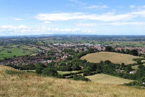 Panoramic view of Glastonbury with church tower and green fields.