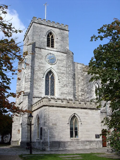 Torre de piedra con ventanas arqueadas y reloj en Poole.