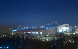 Estadio Falmer iluminado de noche cerca de Brighton, con curvas en forma de silla de montar.