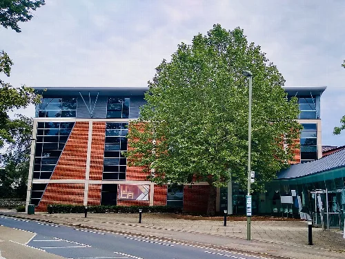 University library building with large glass windows and a tree in front.
