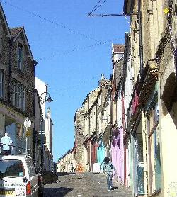 Calle adoquinada en Frome con tiendas coloridas y vista de la colina.