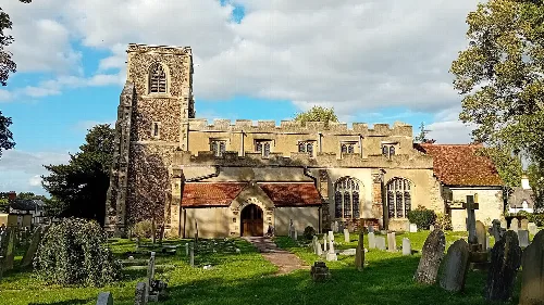 Stone church with tower and graveyard in Arlesey.
