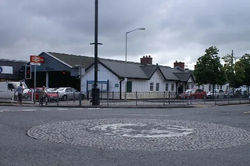 Ansicht des Bahnhofs Pwllheli mit Autos und Wolken am Himmel.
