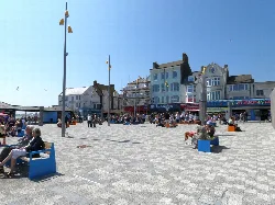 Plaza con tiendas, bancos y personas en Bridlington en un día soleado.