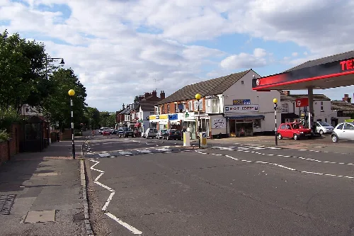 Ansicht der Hauptstraße in Woburn Sands mit Geschäften und Autos.