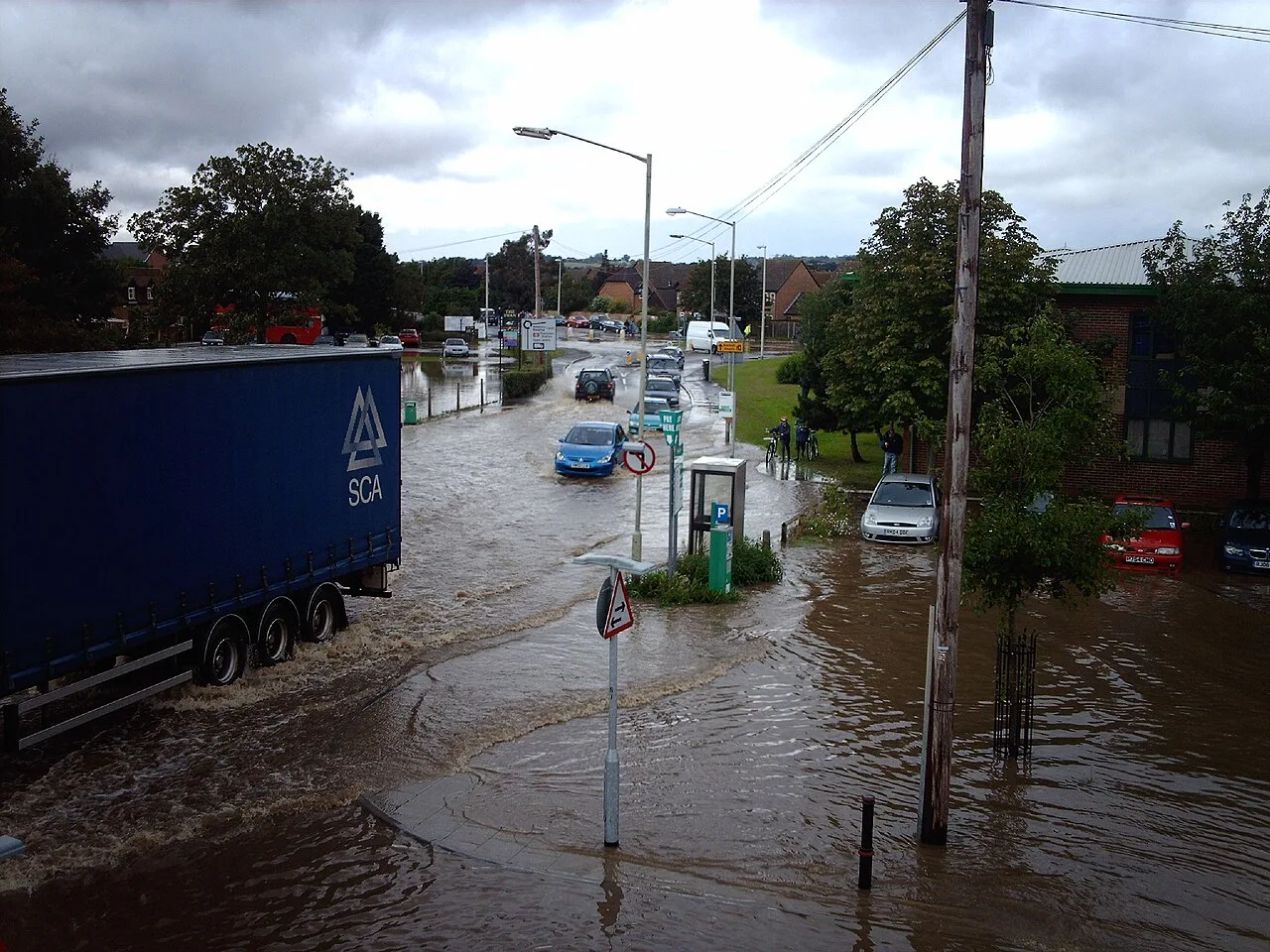 Street flooded with cars and water reaching above the wheels.