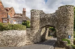Stone city gate with an archway and surrounding stone walls.
