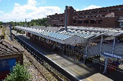 Vista de la estación de tren de Welwyn Garden City desde el puente peatonal con andén y vías.