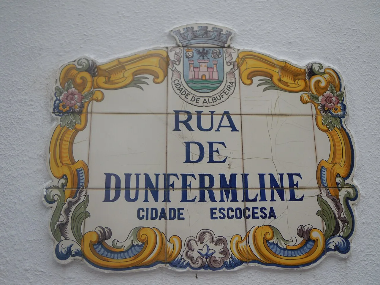 Colorful ceramic street sign with the name 'Rua de Dunfermline' in Portugal.