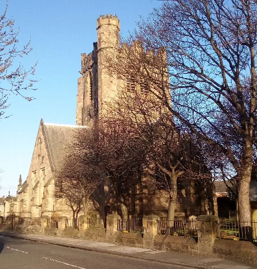 Iglesia de piedra con torre y árboles sin hojas en Blyth.