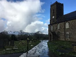 Steinweg führt zur St. James' Kirche mit Friedhof und bewölktem Himmel.
