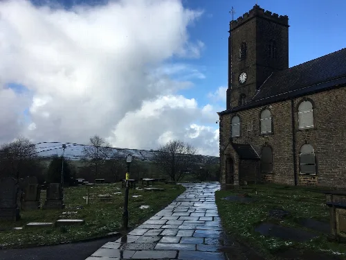 Steinweg führt zur St. James' Kirche mit Friedhof und bewölktem Himmel.