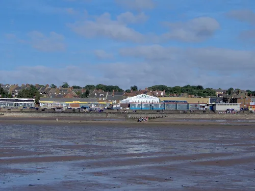 Seaside view of Hunstanton with buildings and pier at low tide.