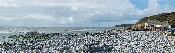 Playa de piedras con mar y cielo, vista hacia el oeste hacia St Donat's.