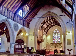Vista del interior de la iglesia con vitrales y techo de madera.