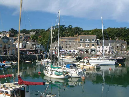 Boats docked in Padstow harbour with buildings behind.