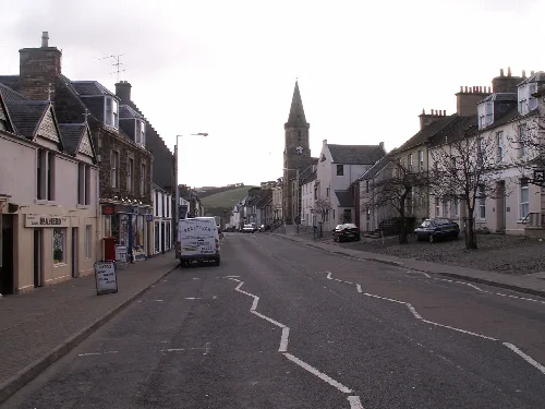 View of Newburgh High Street with buildings and a church steeple.