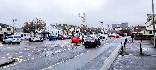 Street scene in Ferryhill with parked cars and wet road.
