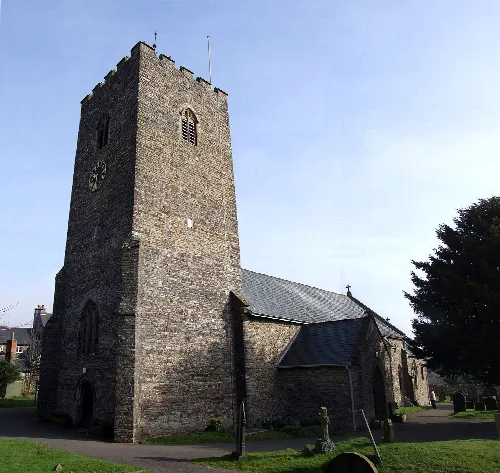 Iglesia de piedra con torre alta y reloj en Bampton, Devon.