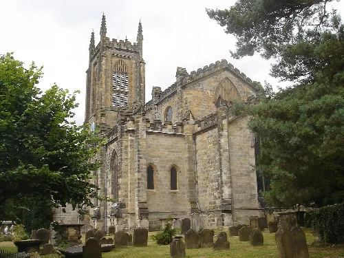 Stone church with tall tower and graveyard in front.