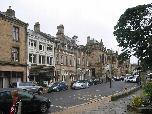 Street view of Beaumont Street in Hexham with historic buildings and parked cars.