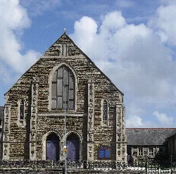 Iglesia de piedra con ventanas y puertas arqueadas, cielo azul con nubes.
