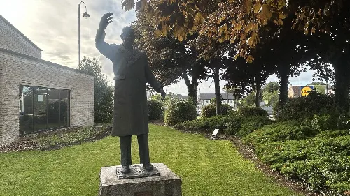 Bronzestatue von William Massey vor der Limavady-Bibliothek mit Bäumen.