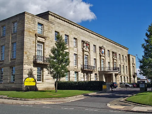Steinernes Gebäude mit Fenstern, Wappen und Balkon in Bury.