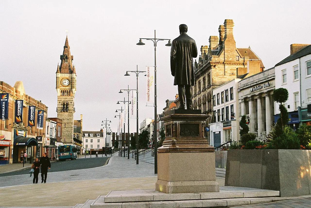 Statue im Stadtzentrum von Darlington mit Geschäften und historischen Gebäuden.