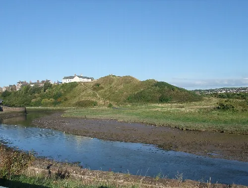 Hügel mit weißem Gebäude oben und Fluss im Vordergrund.