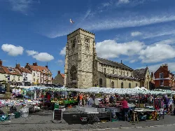 Iglesia de San Miguel con puestos y compradores en Malton.