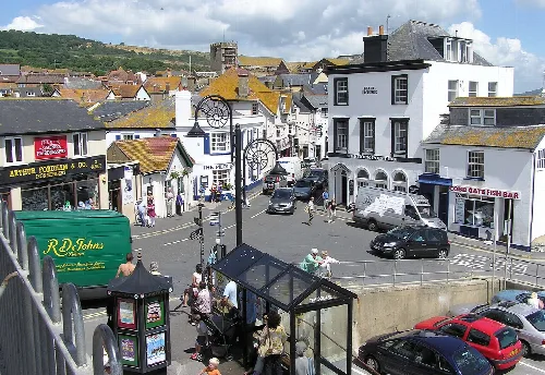 Centro del pueblo con tiendas, coches y personas en Lyme Regis.