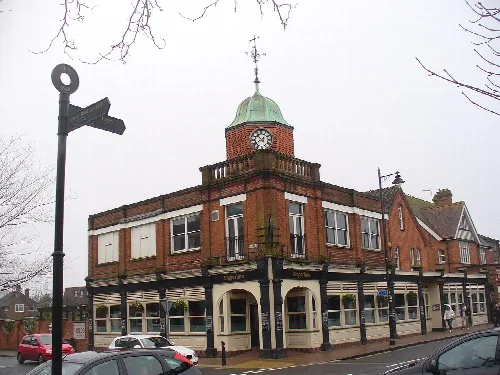 A brick building with a clock tower and a green dome in Fleet.