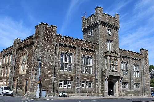 Stone town hall with clock tower and arched entrance in Rothesay.