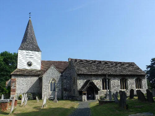 Stone church with a tall spire and graveyard in Great Bookham.