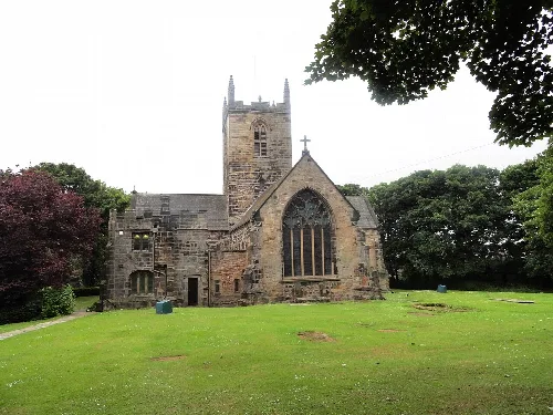 Stone church with a tall tower and large stained glass window.