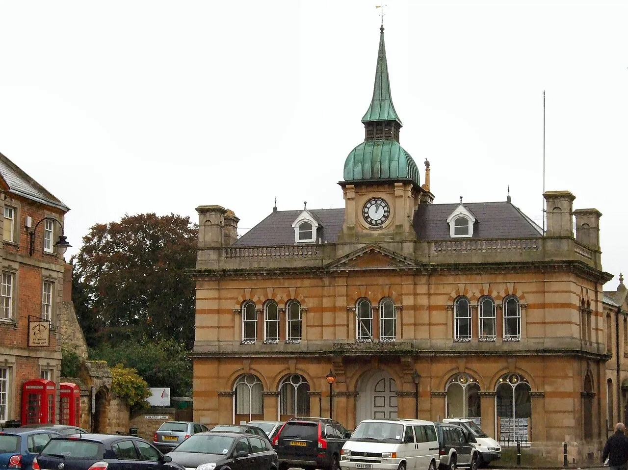 Historisches Rathaus mit Uhrturm und parkenden Autos davor.
