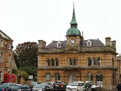 Historisches Rathaus mit Uhrturm und parkenden Autos davor.