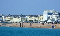 Edificios del paseo marítimo desde el Palace Pier, con playa y velero en primer plano.