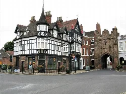Timber-framed building with tower next to a brick medieval gate in Beverley.