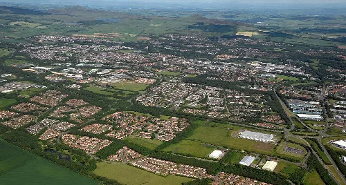Aerial view of Glenrothes with residential areas, green fields, and Lomond Hills in the distance.