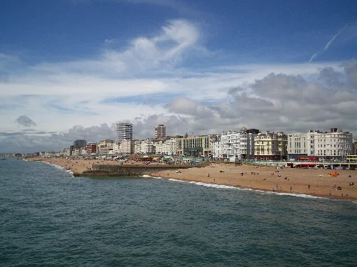 Línea de playa con edificios, playa y cielo nublado en Brighton.