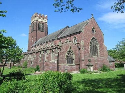 A red brick church with a tower, stained glass windows, and a green lawn in Fenton.