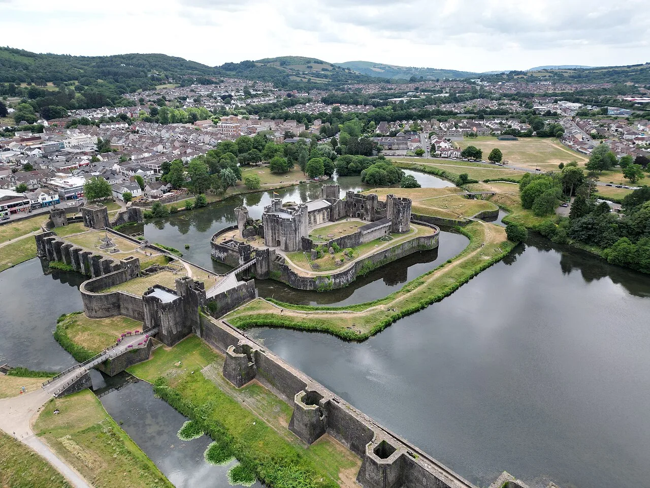 Vista de dron del castillo de Caerphilly con agua y paisaje verde.