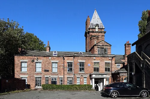 Backsteingebäude mit Turm und Auto vor dem Gebäude in Bebington.