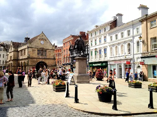 Plaza con estatua, tiendas y personas en Shrewsbury.