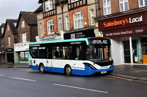 A bus on route 410 parked on a street in Oxted town centre.
