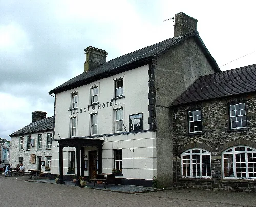 Un edificio blanco con detalles negros y un cartel que dice 'Talbot Hotel' en Tregaron.